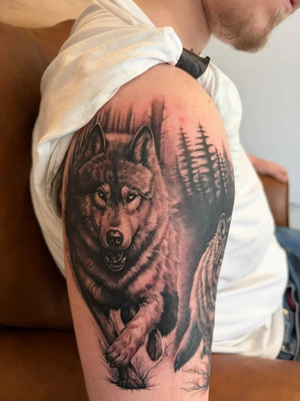 Knurrender Wolf mit Wald am Oberarm, Black & Grey Realismus — Han, Alpenstich