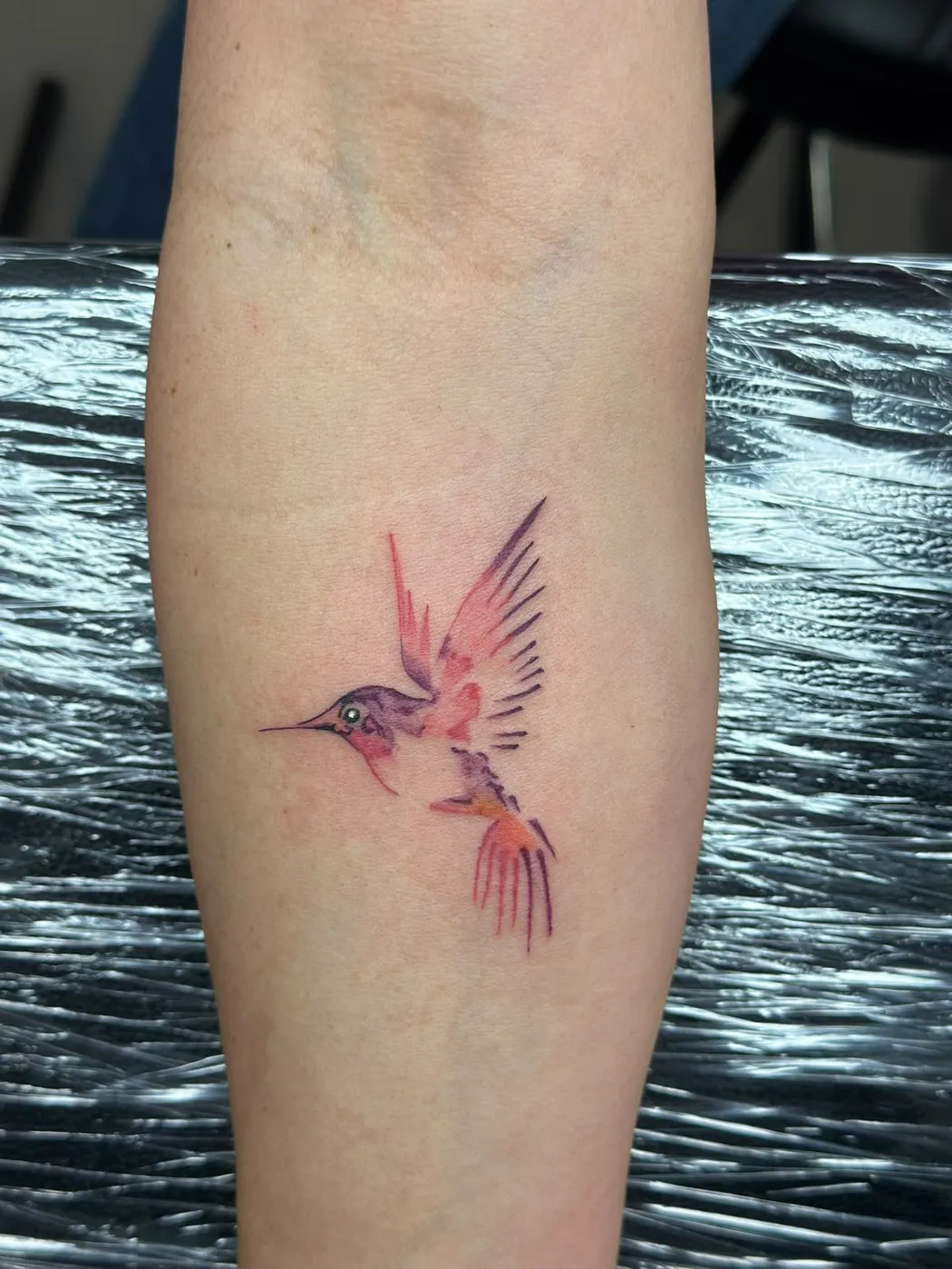 Kolibri im Watercolor-Stil in Rot und Violett am Unterarm — Tschenky, Alpenstich