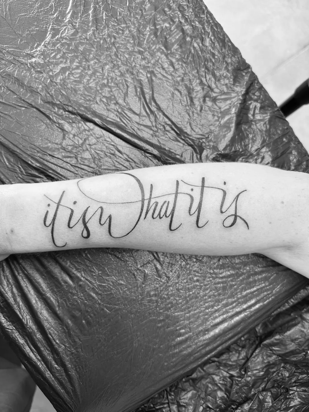 Feines Kalligrafie-Lettering „it is what it is“ am Unterarm — Tschenky, Alpenstich